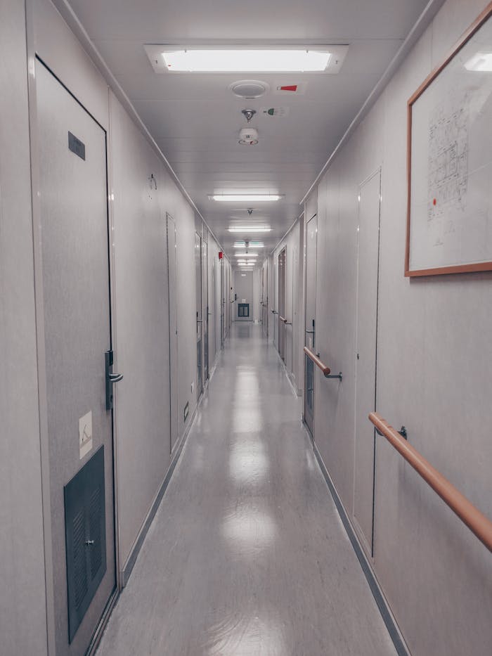 A well-lit industrial hallway with multiple doors and handrails in Ras Laffan, Qatar.